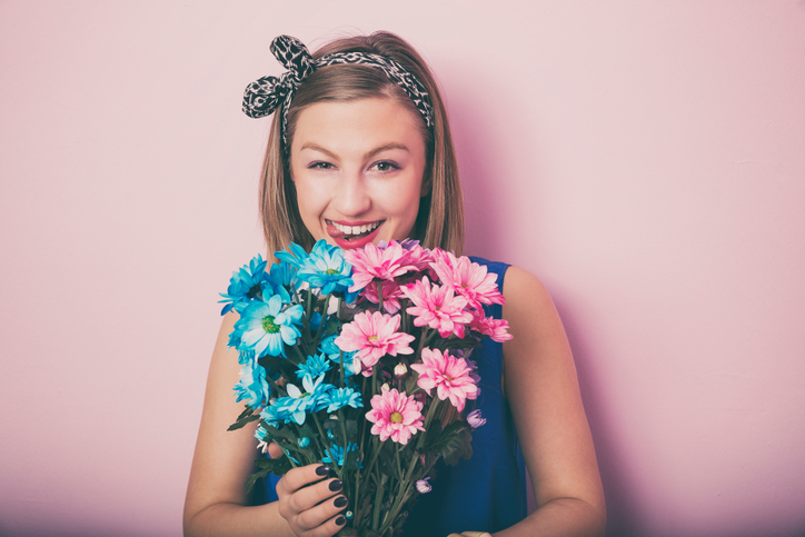 Young attractive beautiful woman smelling flowers.